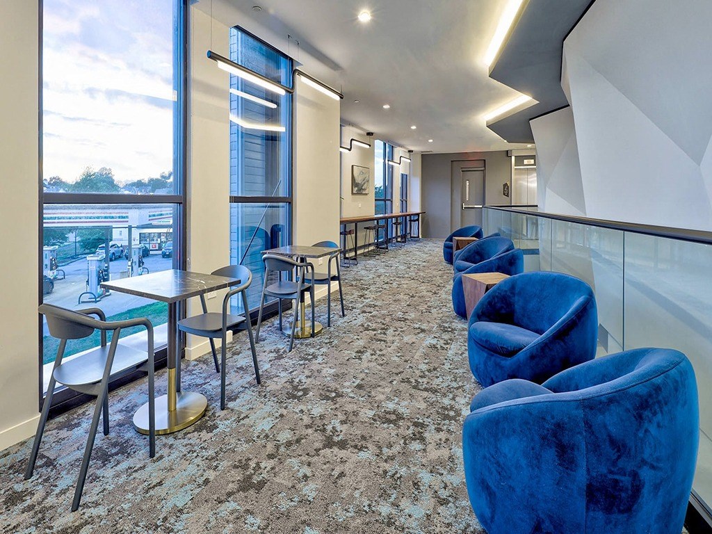 a lounge area with blue chairs and tables and a large window